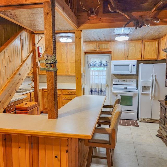 kitchen with a kitchen bar, white appliances, and light tile patterned floors