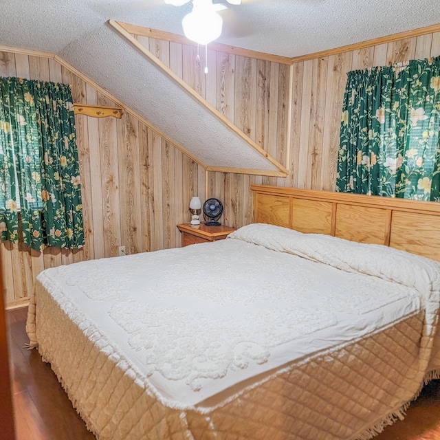 bedroom with wooden walls, wood finished floors, a textured ceiling, and vaulted ceiling