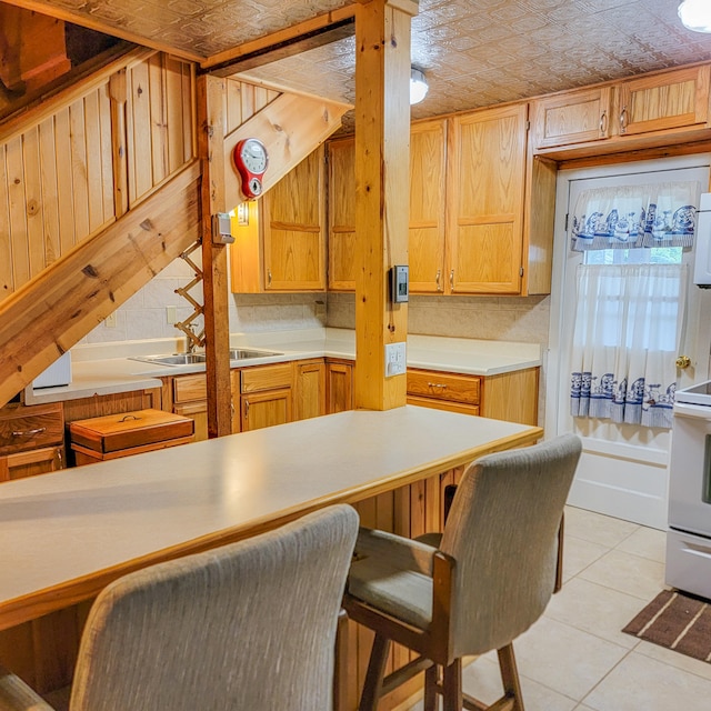 kitchen with sink, light tile patterned floors, white appliances, tasteful backsplash, and a kitchen breakfast bar