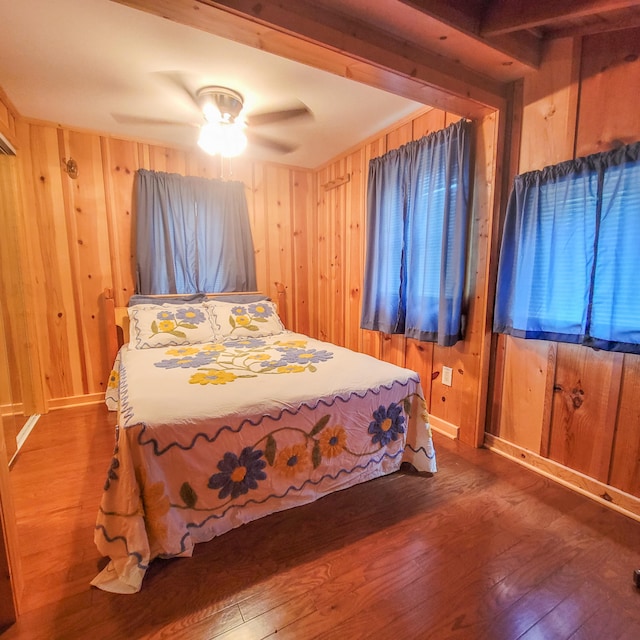 bedroom with hardwood / wood-style floors, wooden walls, and ceiling fan