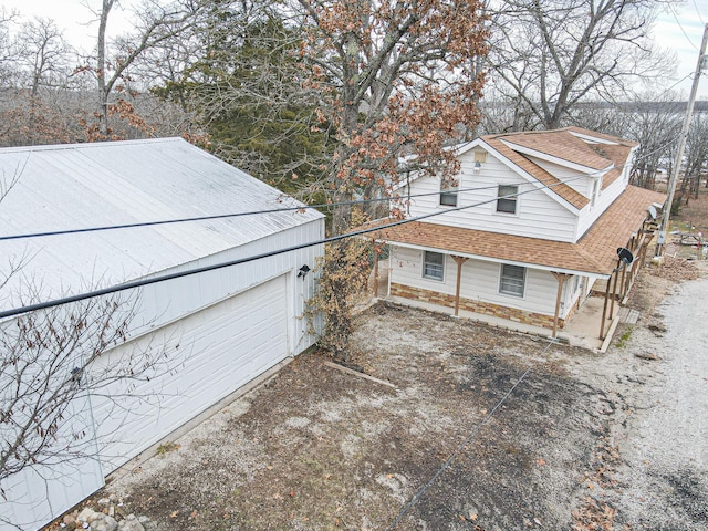 view of side of property featuring roof with shingles and a garage