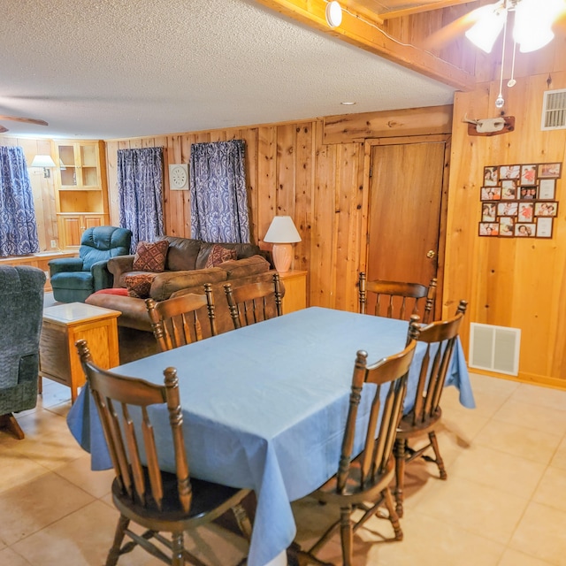 dining area with wood walls, a textured ceiling, and ceiling fan