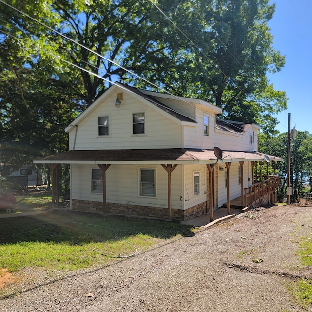 view of side of home with a porch and stone siding