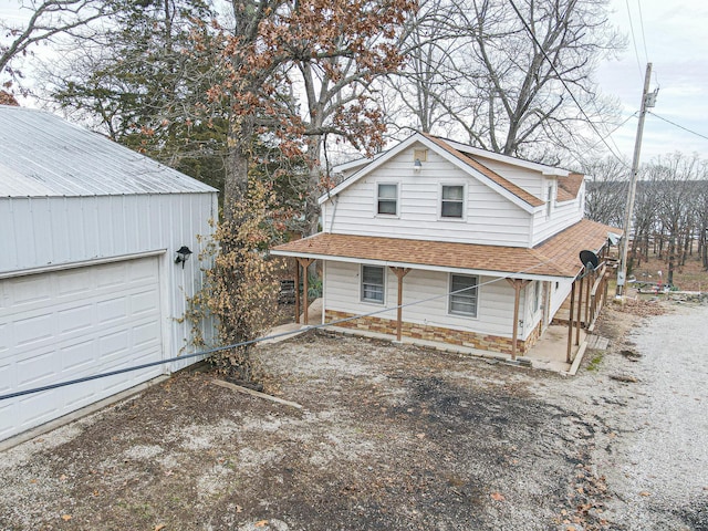 view of home's exterior with a porch, roof with shingles, and a garage