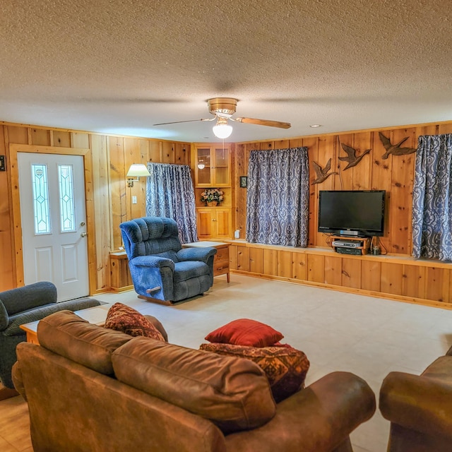 living room with ceiling fan, wood walls, and a textured ceiling