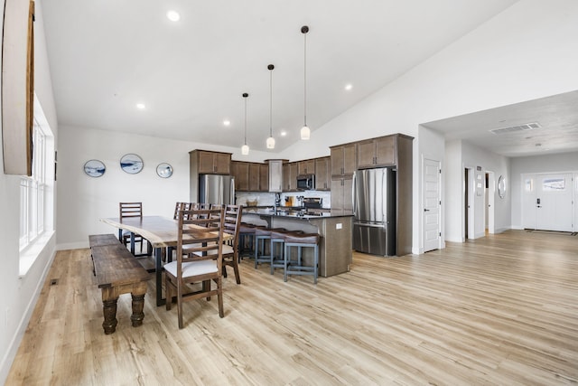 dining space featuring high vaulted ceiling, a wealth of natural light, and light hardwood / wood-style floors