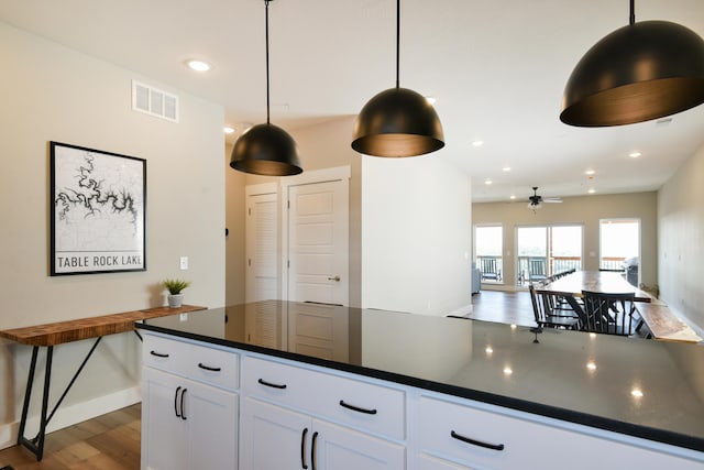 kitchen with ceiling fan, white cabinets, decorative light fixtures, and dark hardwood / wood-style flooring