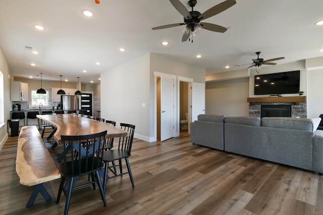 dining room featuring a fireplace, ceiling fan, and dark hardwood / wood-style flooring