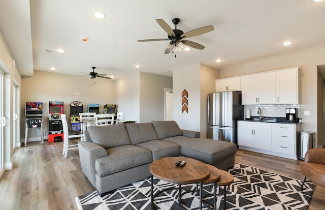 living room featuring light wood-type flooring, ceiling fan, and sink