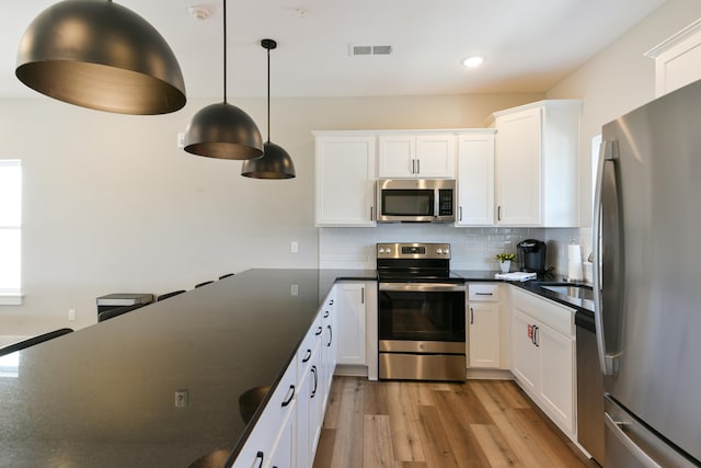 kitchen featuring decorative light fixtures, light hardwood / wood-style flooring, stainless steel appliances, and white cabinets