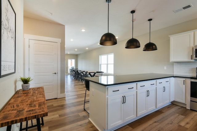 kitchen with white cabinets, hanging light fixtures, and dark hardwood / wood-style flooring