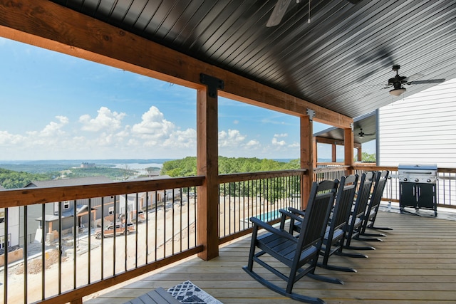 wooden deck with a water view, a grill, and ceiling fan