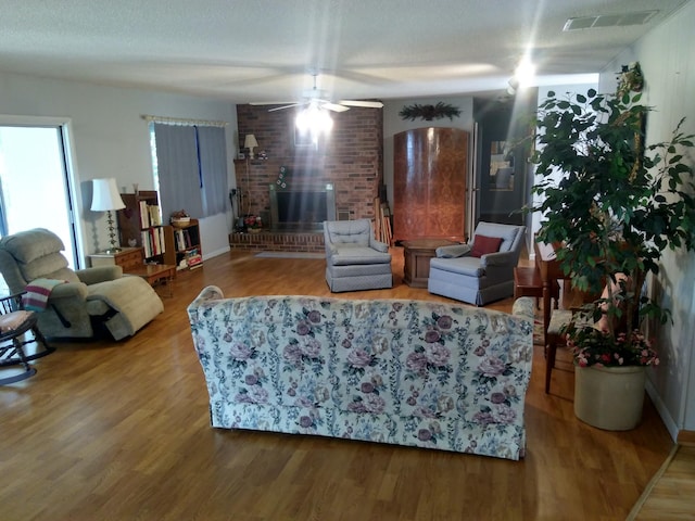 living room featuring wood-type flooring, a textured ceiling, and ceiling fan