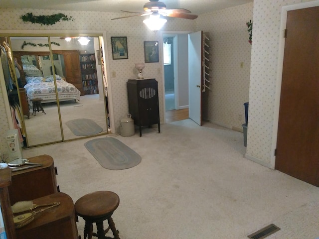 carpeted bedroom featuring ceiling fan and a closet