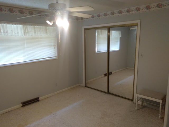 unfurnished bedroom with ceiling fan, a closet, and light carpet