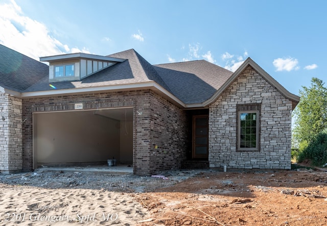 view of front of property featuring roof with shingles, brick siding, stone siding, and a garage