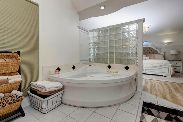 bathroom featuring vaulted ceiling, tile walls, tile patterned flooring, and a tub