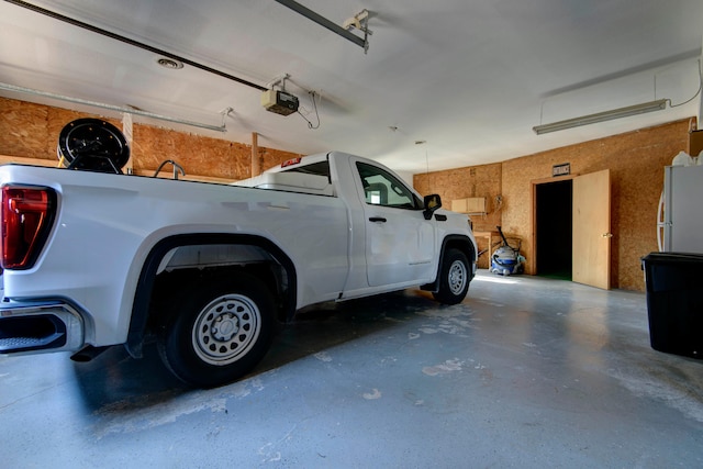 garage with a garage door opener and white refrigerator