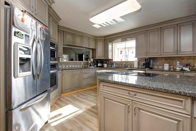 kitchen featuring decorative backsplash, dark stone countertops, sink, light hardwood / wood-style flooring, and appliances with stainless steel finishes