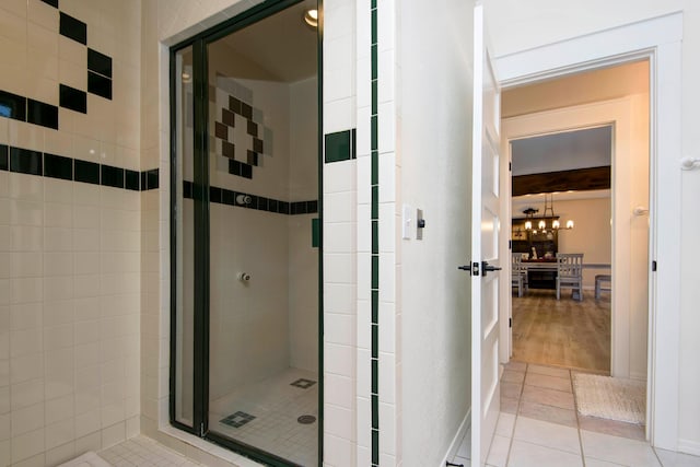 bathroom featuring tile patterned flooring, a shower with door, and a chandelier