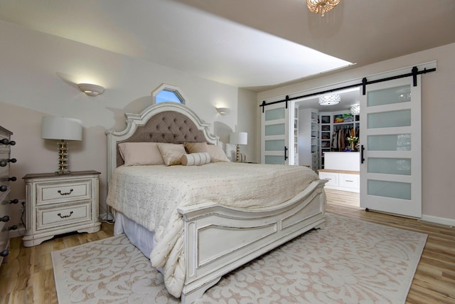 bedroom with a barn door, a spacious closet, a closet, and light wood-type flooring