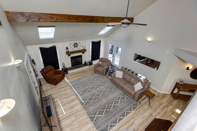 living room featuring light wood-type flooring, ceiling fan, a large fireplace, french doors, and high vaulted ceiling