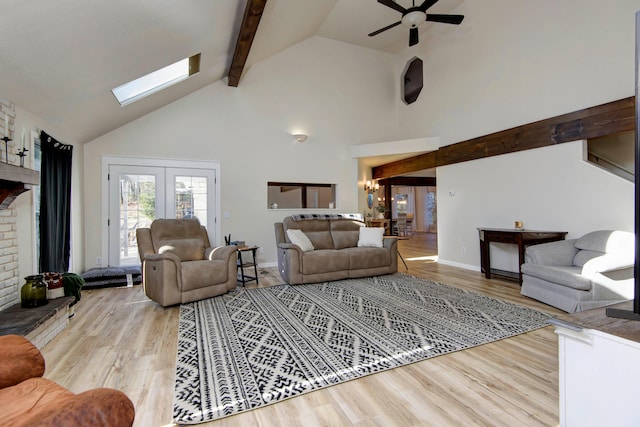 living room featuring light wood-type flooring, high vaulted ceiling, ceiling fan with notable chandelier, a skylight, and beam ceiling