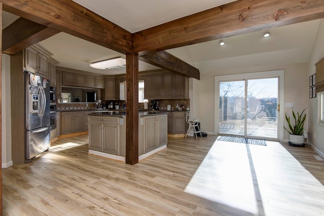 kitchen featuring vaulted ceiling with beams, a kitchen island, stainless steel appliances, light wood-type flooring, and decorative backsplash