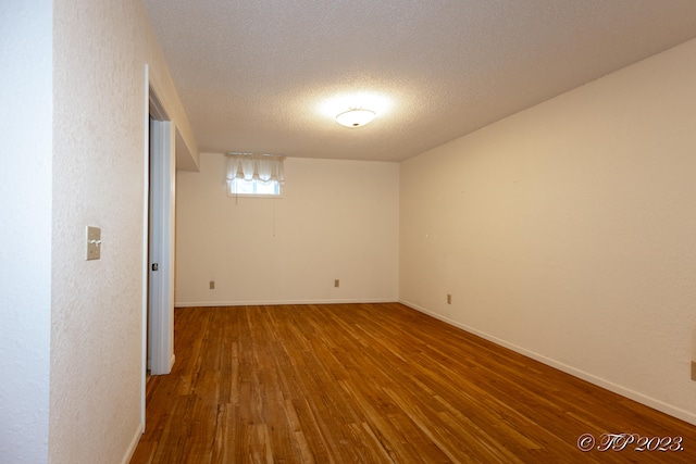 spare room featuring wood-type flooring and a textured ceiling