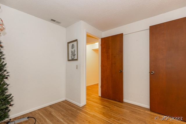 spare room with light hardwood / wood-style floors and a textured ceiling