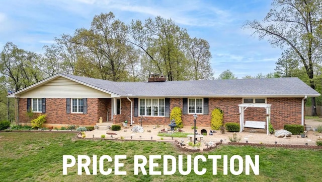 ranch-style house with a front lawn, brick siding, and a chimney