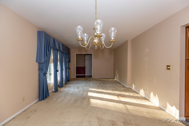 carpeted empty room with a notable chandelier