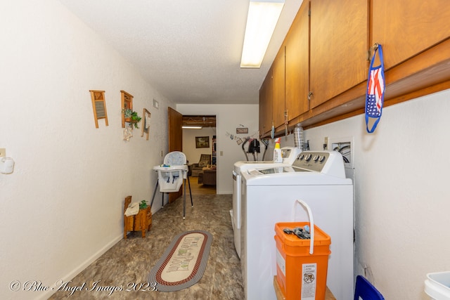 laundry room with a textured ceiling, washer and clothes dryer, and cabinets