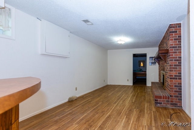 basement featuring a brick fireplace, hardwood / wood-style floors, and a textured ceiling