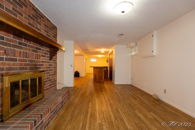 unfurnished living room featuring a textured ceiling, a fireplace, hardwood / wood-style floors, and indoor bar