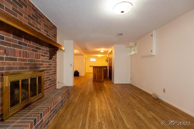 4565 State Route Cc, West Plains, MO 65775 - unfurnished living room featuring indoor bar, a brick fireplace, wood finished floors, and a textured ceiling