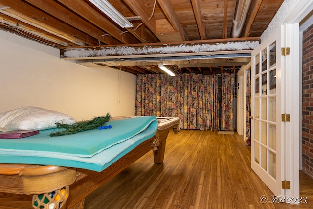 playroom with wood-type flooring and brick wall