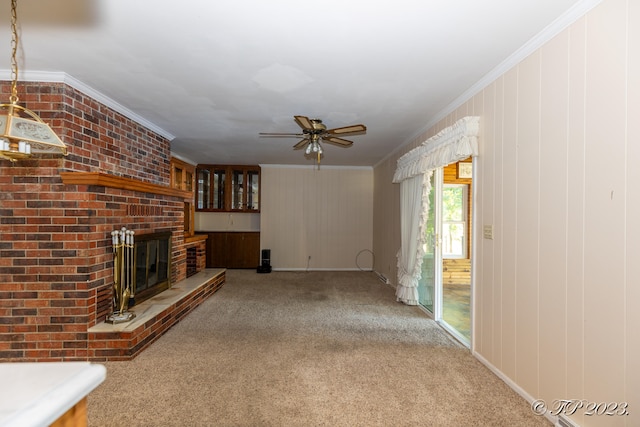 unfurnished living room featuring ceiling fan, a fireplace, crown molding, and carpet flooring