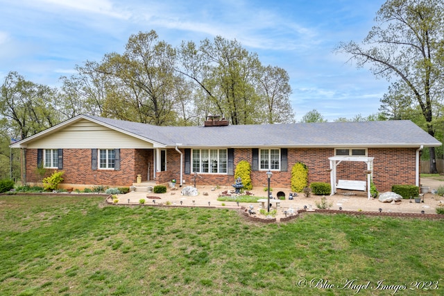 ranch-style house featuring brick siding, a chimney, and a front yard