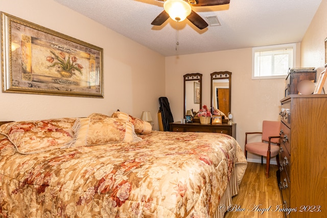 bedroom with a textured ceiling, ceiling fan, and light hardwood / wood-style flooring