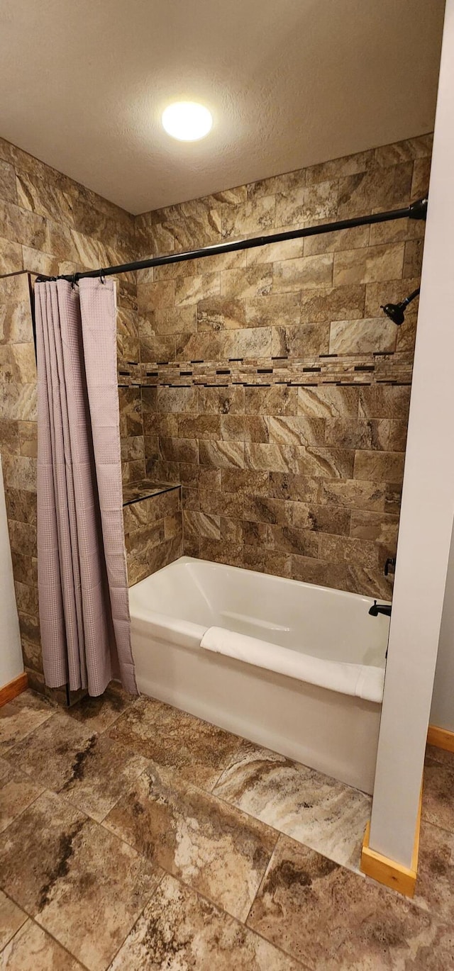 bathroom with shower / tub combo with curtain and a textured ceiling