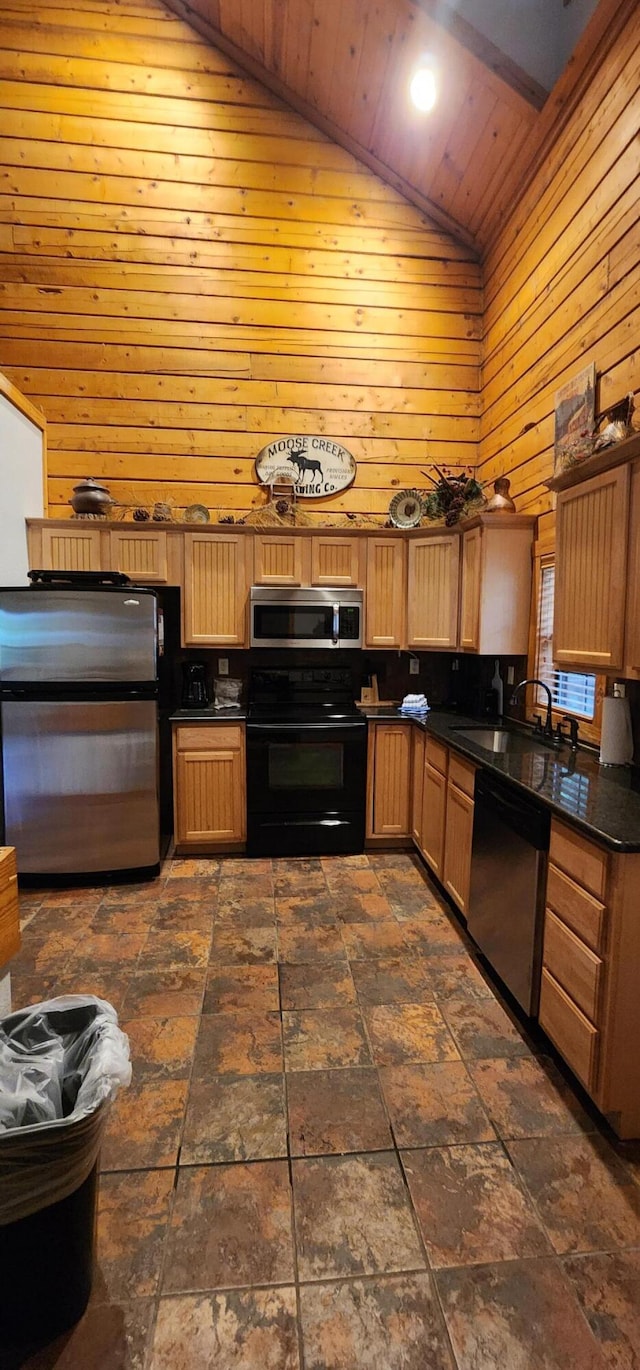 kitchen with appliances with stainless steel finishes, wood walls, sink, and high vaulted ceiling