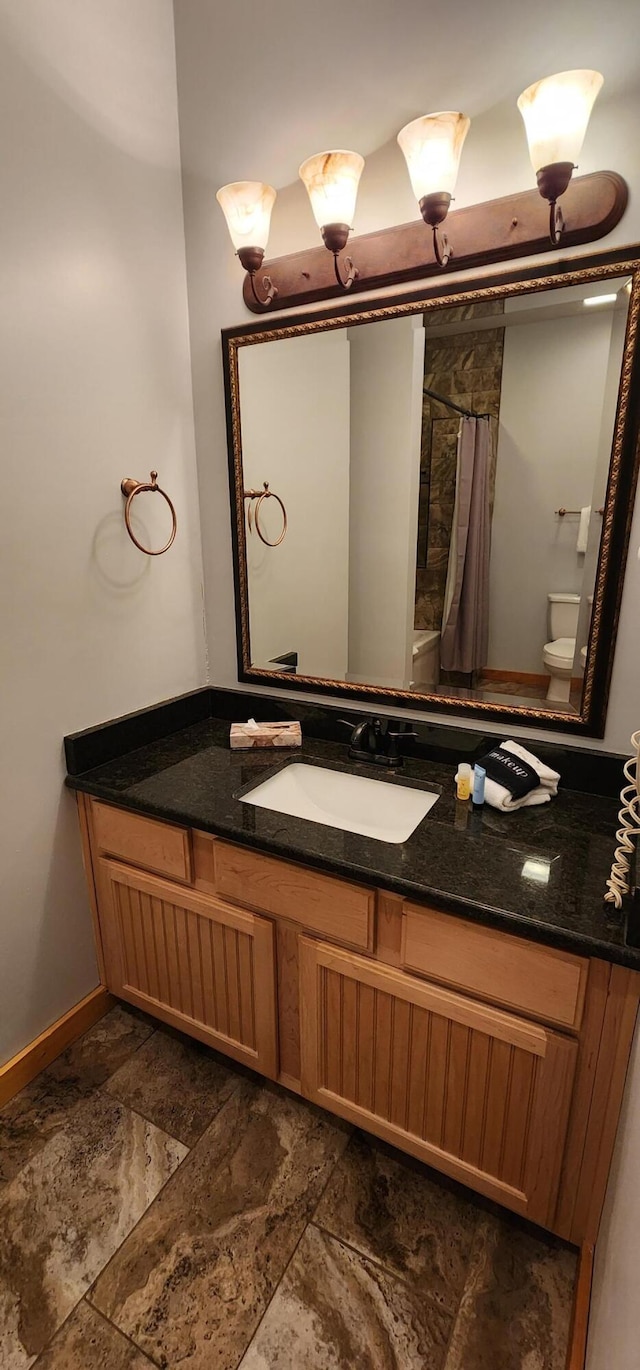 bathroom with walk in shower, vanity, and toilet