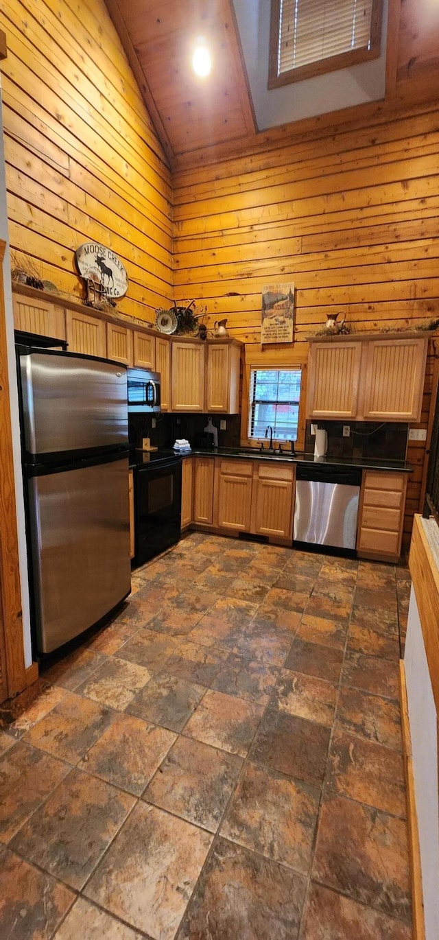 kitchen with wooden walls, appliances with stainless steel finishes, sink, and high vaulted ceiling