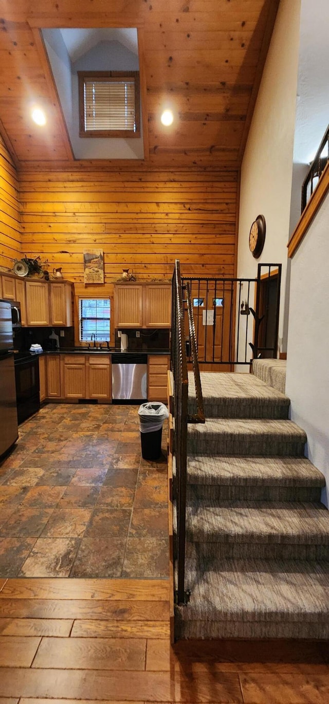 stairway with high vaulted ceiling, wood walls, and wood ceiling