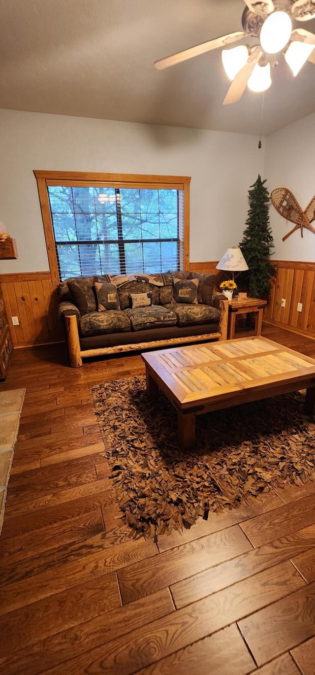 unfurnished living room with wood walls, hardwood / wood-style floors, and ceiling fan