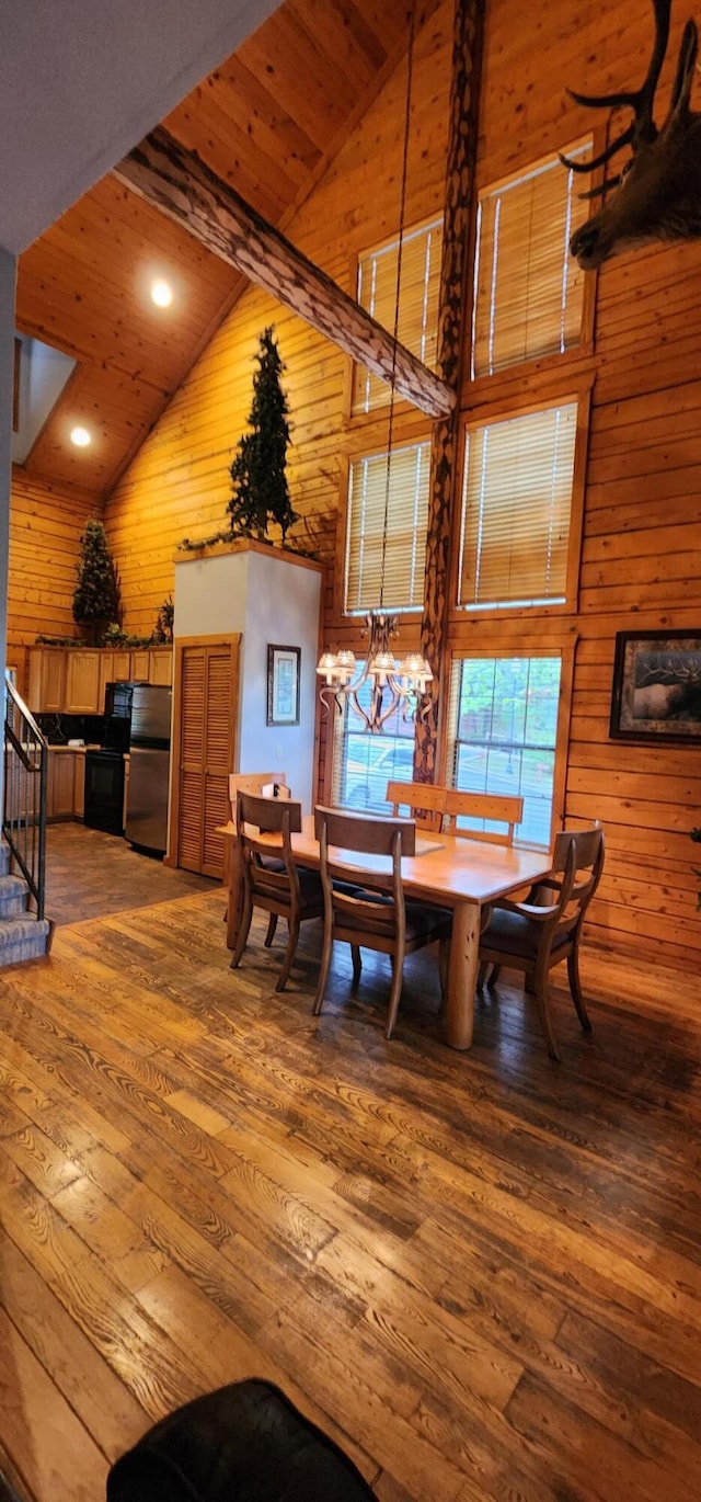 dining room with wood walls, high vaulted ceiling, hardwood / wood-style floors, and beamed ceiling