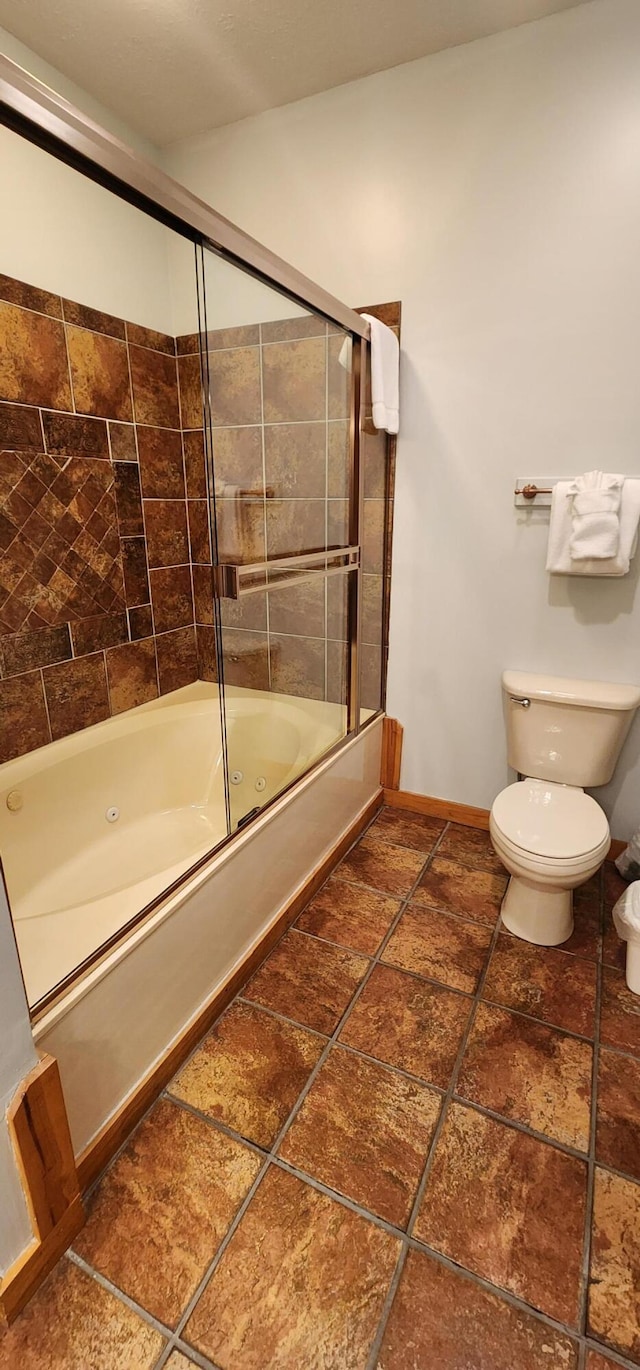 bathroom with bath / shower combo with glass door and toilet