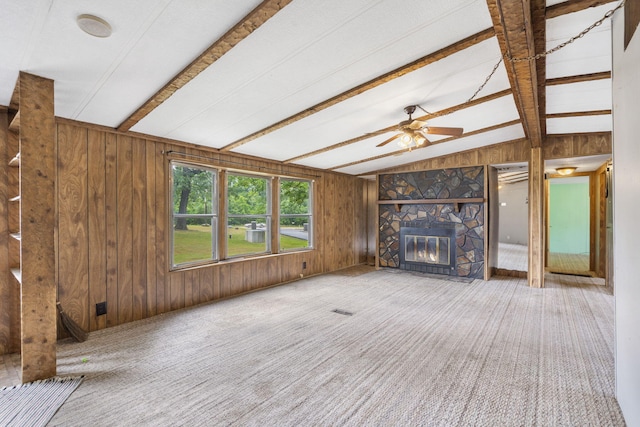 unfurnished living room featuring lofted ceiling with beams, ceiling fan, a fireplace, wood walls, and carpet flooring