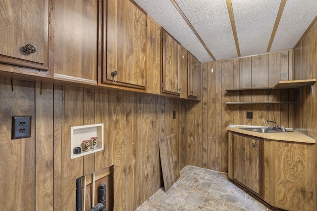 laundry area with washer hookup, cabinets, wooden walls, and sink